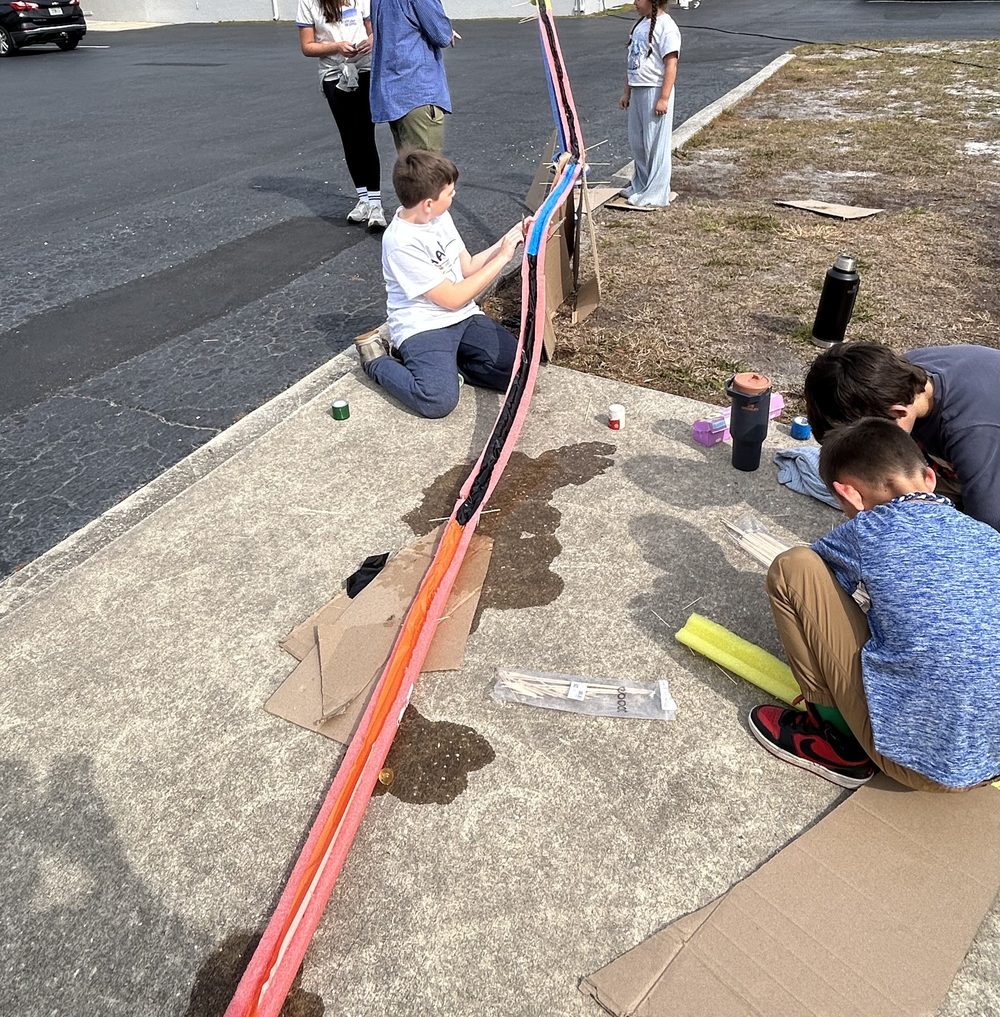 Students building and testing a straw rocket outdoors