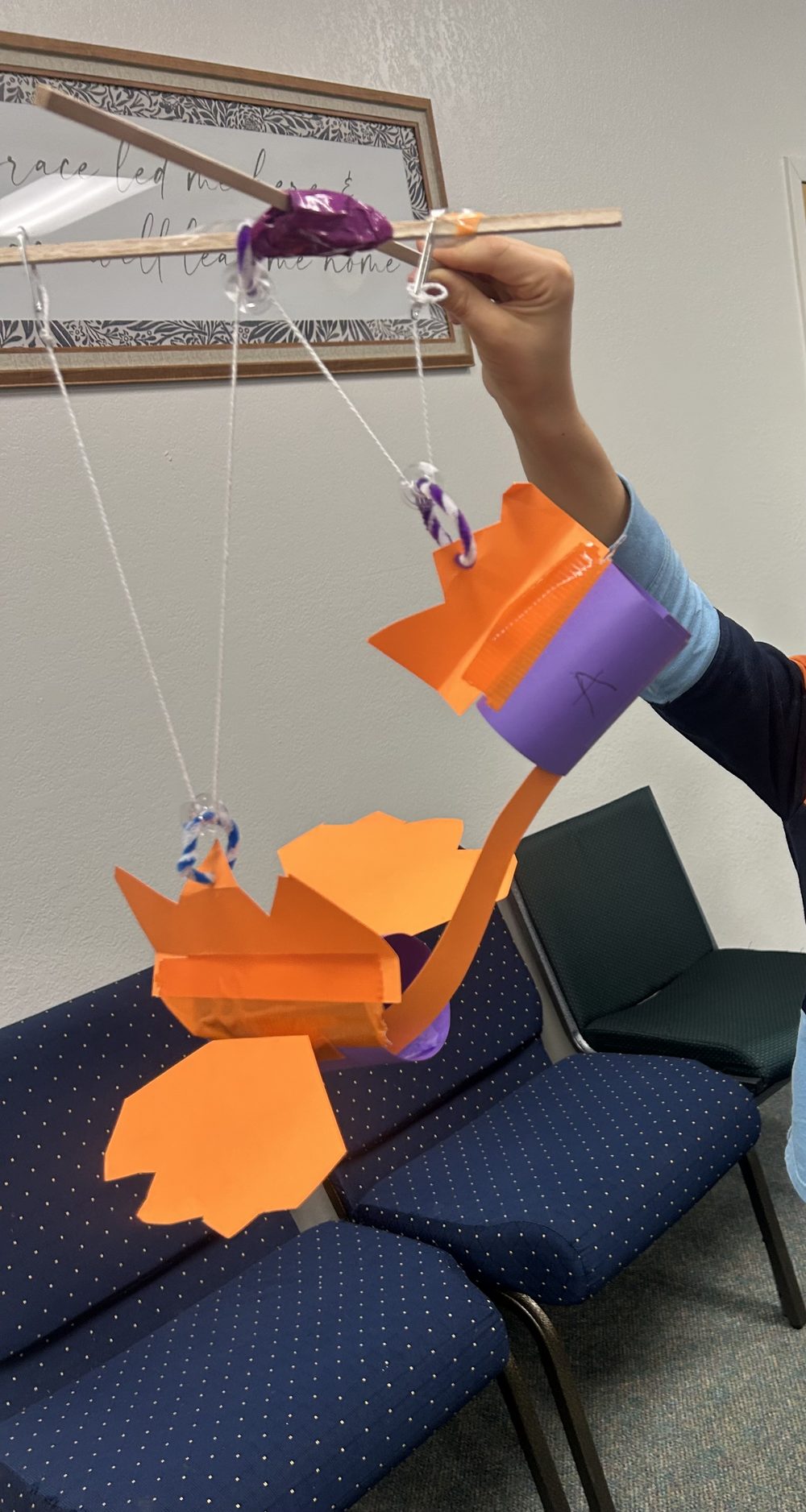 Student building a paper-and-dowel mechanical claw model