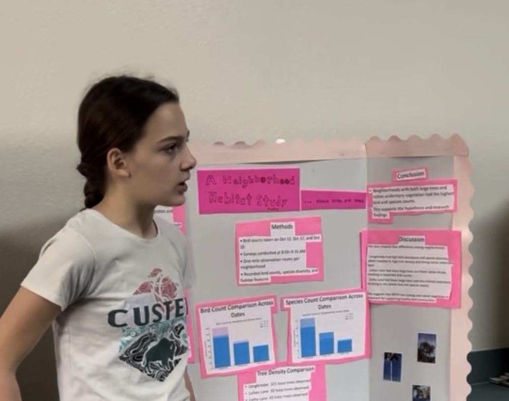 Student presenting her science fair project board